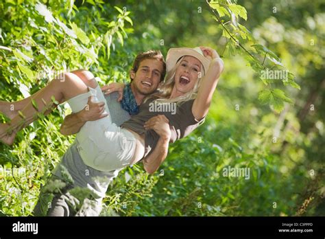 Man Carrying Woman In Forest Smiling Stock Photo Alamy