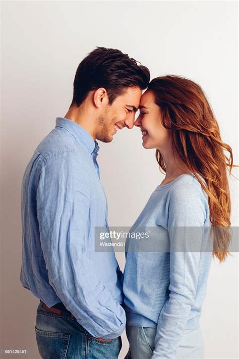 Happy Young Couple Standing Face To Face In Front Of White Background