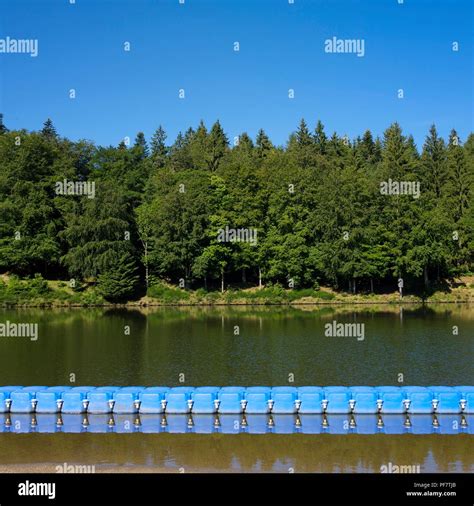 Row Of Blue Floats Separating The Waters Of A Tree Lined Lake Auvergne