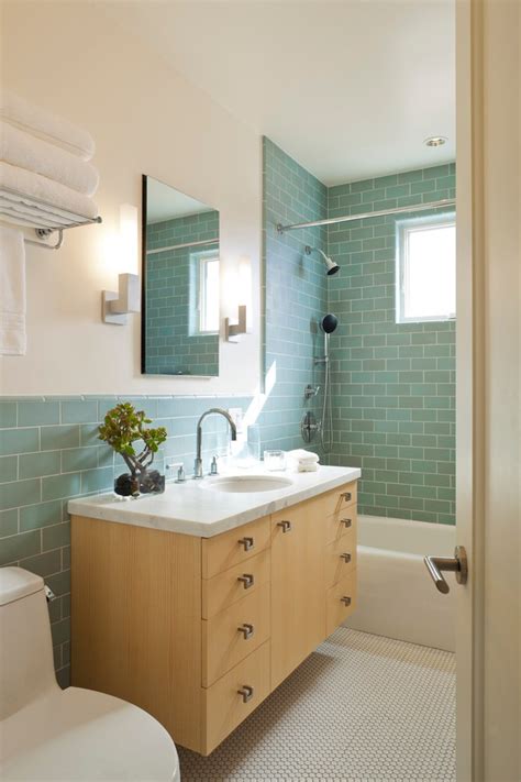 Charming white and green bathroom features wall clad in white subway tiles on the lower walls and green upper walls lit by two sconces mounted on either side of a white framed medicine cabinet positioned over a marble ledge fixed above a white pedestal bathroom sink. san francisco green ceramic subway tile bathroom modern ...