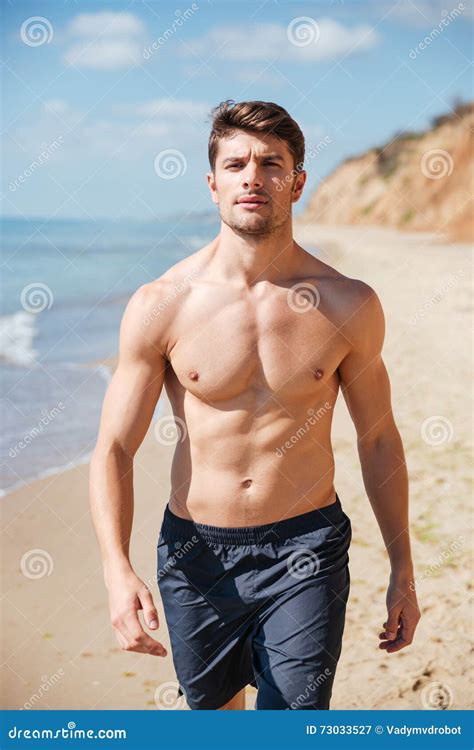 Confident Shirtless Young Man Walking Along The Beach Stock Image