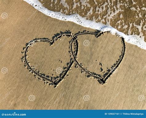 Two Connected Hearts Drawn On The Beach Sand With Sea Waves Stock Image