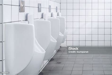 foto de fileira dos urinóis brancos no toalete público do banheiro dos homens com parede branca
