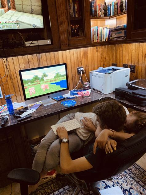 Two People Hugging Each Other While Sitting In Front Of A Computer Desk With A Monitor And
