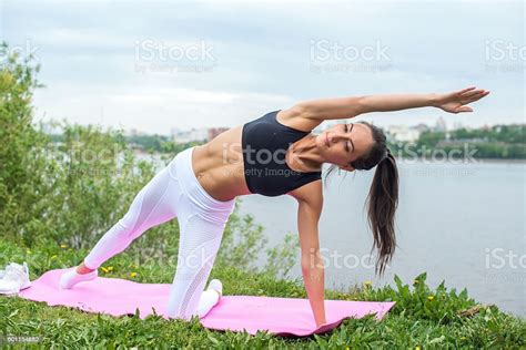 Woman In A Yoga Pose With Her Arm Reaching Overhead Stock Photo