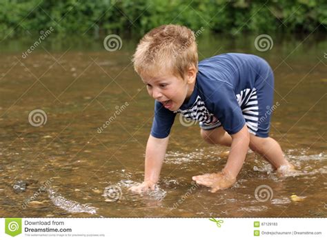 Little Boy Trying To Catch A Fish In The Middle Of Stream Stock Image