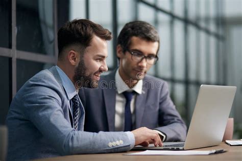 Two Handsome Businessmen Working Together On A Project Sitting Stock