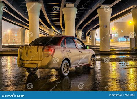 Dirty Red Car On A Parking Under The Bridge At Night Stock Photo