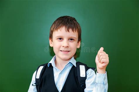 Funny Schoolboy Grimaces Near The Green School Board In The Classroom