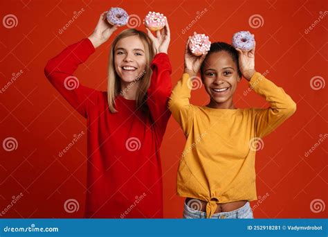 Multiracial Two Girls Laughing While Making Fun With Donuts Stock Image