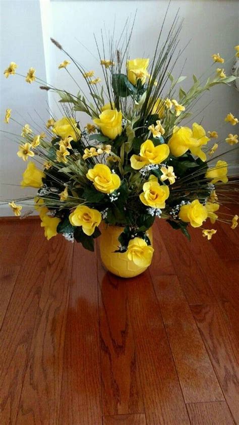 A Vase Filled With Yellow Flowers On Top Of A Wooden Floor