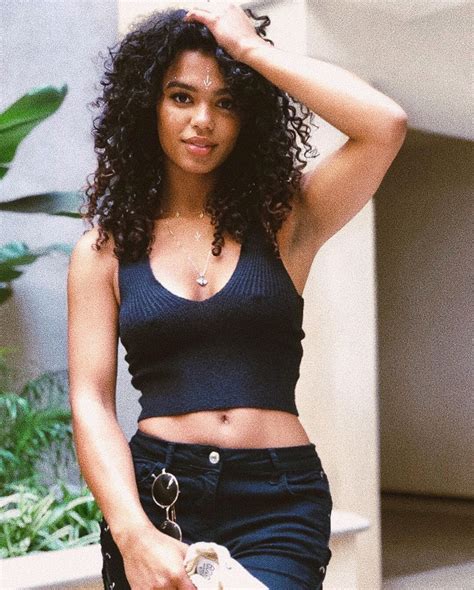 a woman with curly hair is posing for the camera while holding her purse and looking at the camera