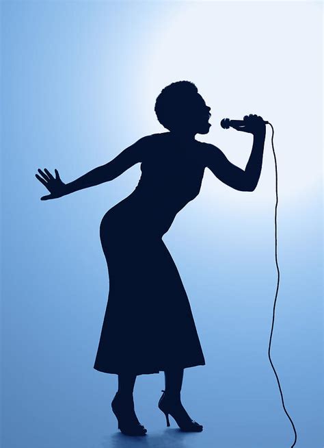 silhouette of female singer singing on microphone photograph by pm images