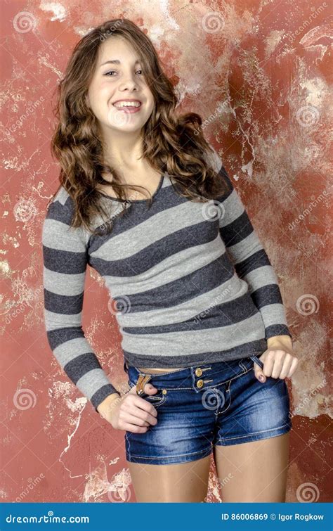 Young Cheerful Girl In Denim Shorts And A Striped Sweater Walking In