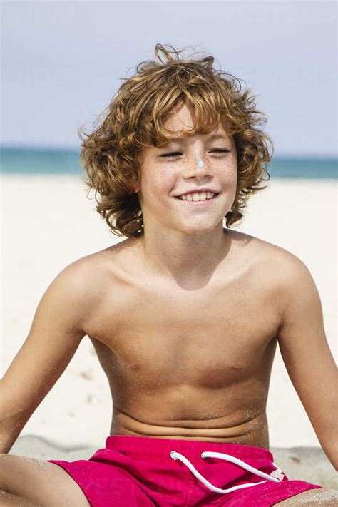 Spain Boy Sitting On Beach Smiling Stock Photo