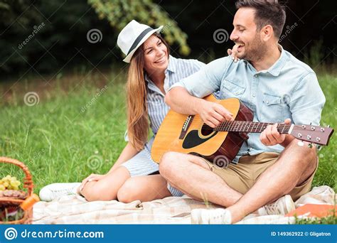 Romantic Young Couple Having A Great Time On A Picnic Playing Guitar