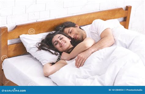 Loving Man And Woman Sleeping In Bed Embracing Each Other Stock Photo