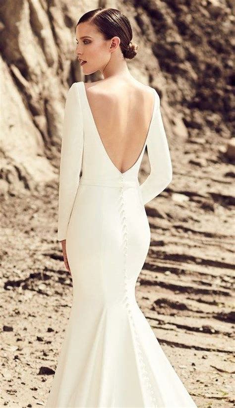 picture of a modern plain mermaid wedding dress with long sleeves a row of buttons and a cutout