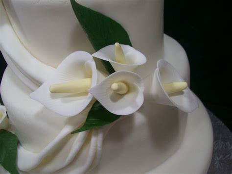 A Close Up Of A White Cake With Flowers On The Top And Green Leaves