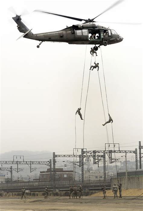 a uh 60 black hawk helicopter hovers as 2nd infantry division rappel masters steady ropes