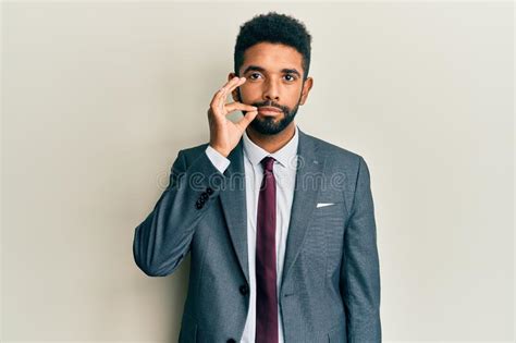 Handsome Hispanic Man With Beard Wearing Business Suit And Tie Mouth And Lips Shut As Zip With