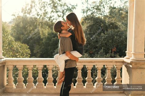 Side View Of Boyfriend Holding Girlfriend On Hands Over Ornate Marble