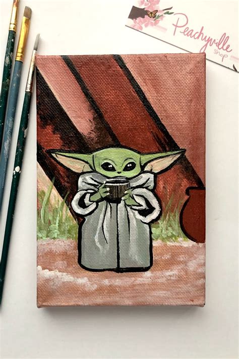 A Painting Of A Baby Yoda Holding An Apple Next To Two Pencils On A Table