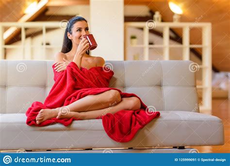 A Beautiful Woman On The Sofa Wrapped In A Blanket And Enjoying Stock