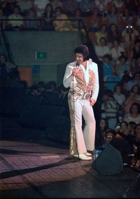 elvis presley standing on stage in front of an audience