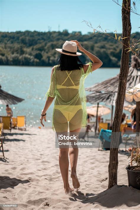 eine attraktive junge schwarzhaarige frau ist am strand sie steuert auf das wasser zu und trägt