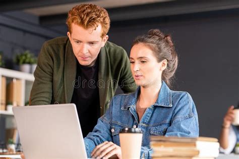 Young Confident Female Designer And Her Male Colleague Looking At