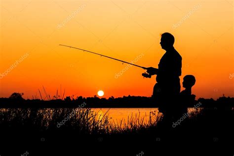Padre E Hijo Pescando En El Fondo Del Atardecer Del Río