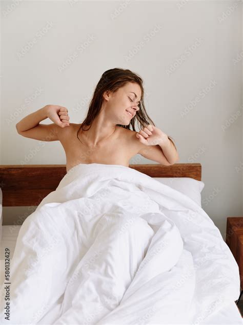 Zdj Cie Stock A Woman Sits On A Bed In The Bedroom And Covers Her Body
