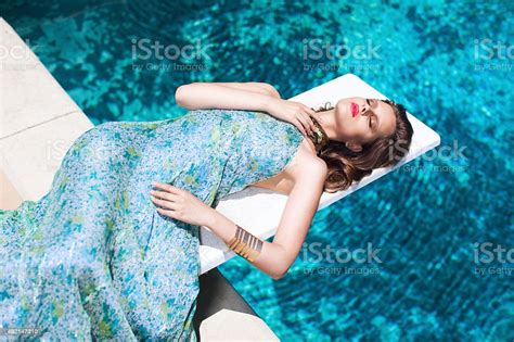 Beautiful Elegant Model Wearing Pretty Dress Laying By Pool Stock Photo