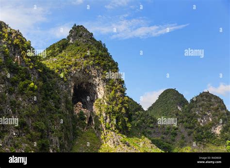 Tall Green Mountain Peak And Limestone Cave Entrance In Ma Pi Long Pass