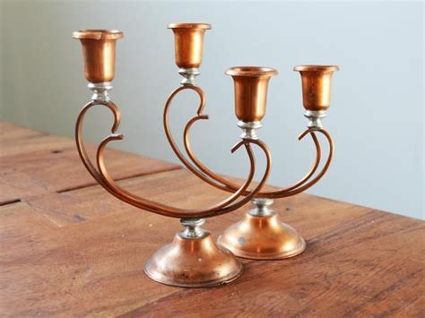 Three Copper Candlesticks Sitting On Top Of A Wooden Table