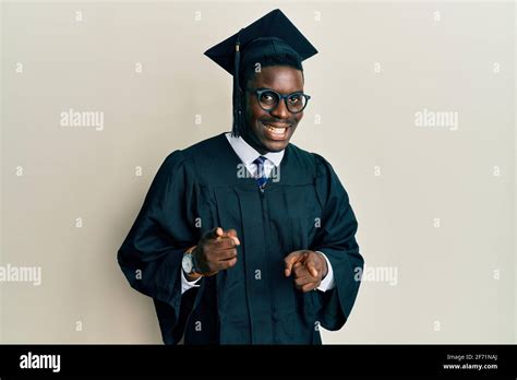Handsome Black Man Wearing Graduation Cap And Ceremony Robe Pointing