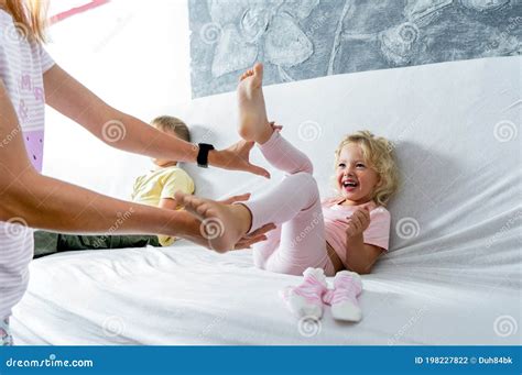 Mom Tickles Her Little Daughter S Feet The Girl Laughs Merrily Stock