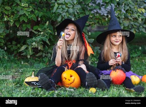 Two Funny Little Girls In Witch Costumes Eating Halloween Candy Stock