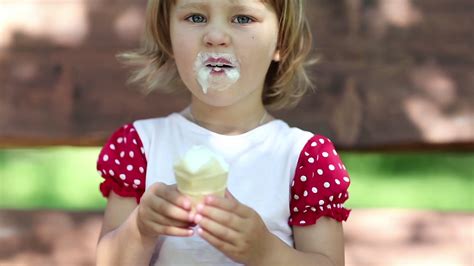 little cheery girl sits on the swing bench eats ice cream and licks her lips stock video footage
