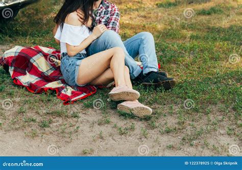 Loving Couple Sits On A Red Plaid In The Woods And Embracethe Couple Is Kissing Stock Image