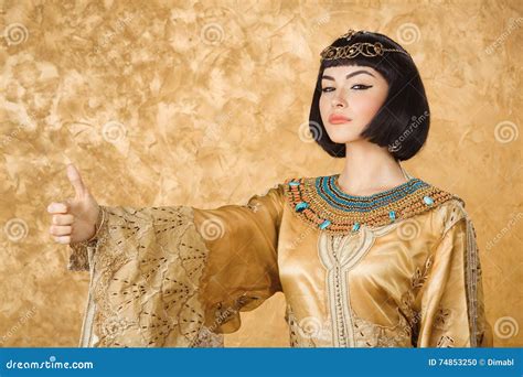 Serious Egyptian Woman Like Cleopatra With Thumbs Up Gesture On Golden Background Royalty Free