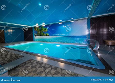 A Modern Large Indoor Pool With Blue Lighting And A Waterfall Stock