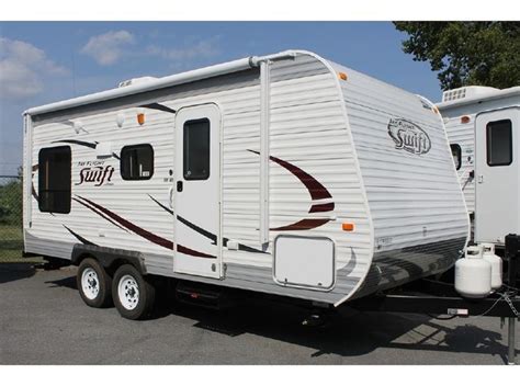 An Rv Parked In A Parking Lot Next To Another Trailer With The Word