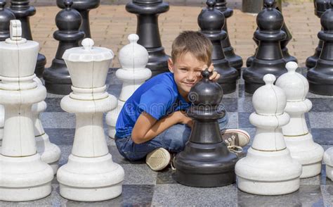 Smiling Boy Sitting On Outdoor Chess Game Board In The Park Stock Image