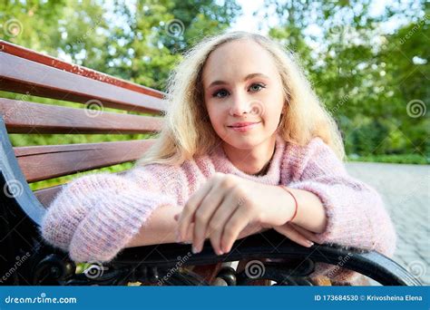 Pretty Teenage Girl 14 16 Year Old With Curly Long Blonde Hair In The Green Park On The Bench In