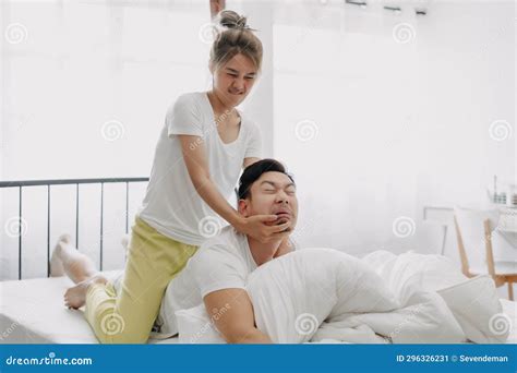 Funny Couple Wife Giving Husband Hurt Massage In White Bedroom Stock