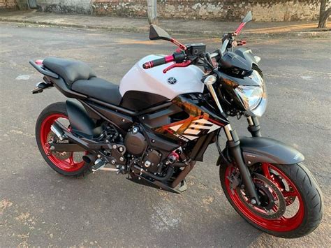 A Motorcycle Parked On The Street In Front Of A Building With Red Rims