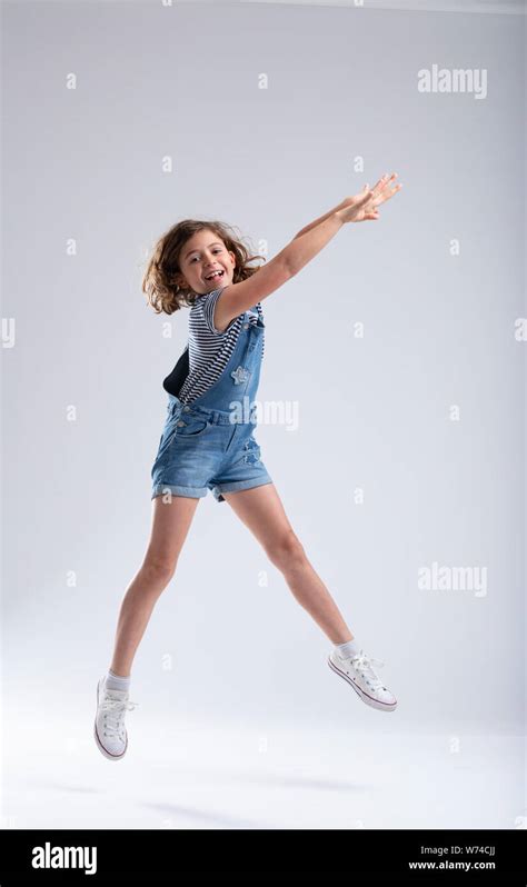Graceful Little Girl Stretching Her Arms As She Jumps High Into The Air