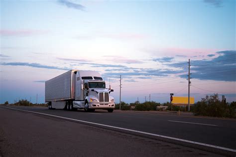 Semi Truck Trailer Going On Arizona Road In Sunset Stock Photo